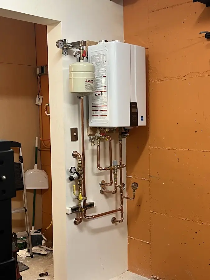 Plumbing technician inspecting water heater connections in Newtown